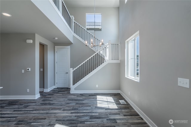 interior space featuring a towering ceiling, wood-type flooring, and a notable chandelier