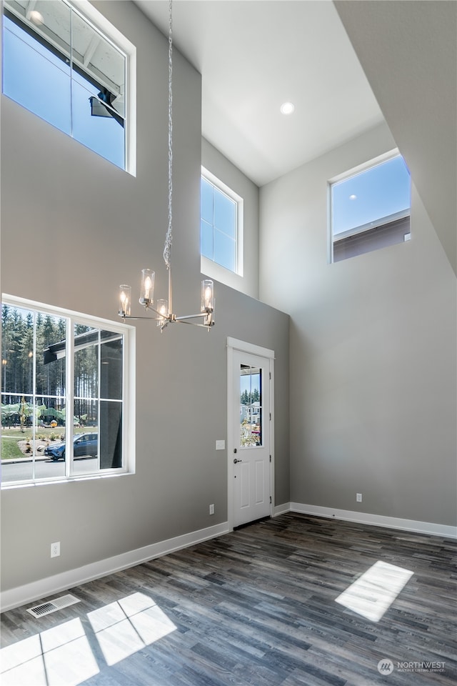 entrance foyer featuring a high ceiling, wood-type flooring, and an inviting chandelier