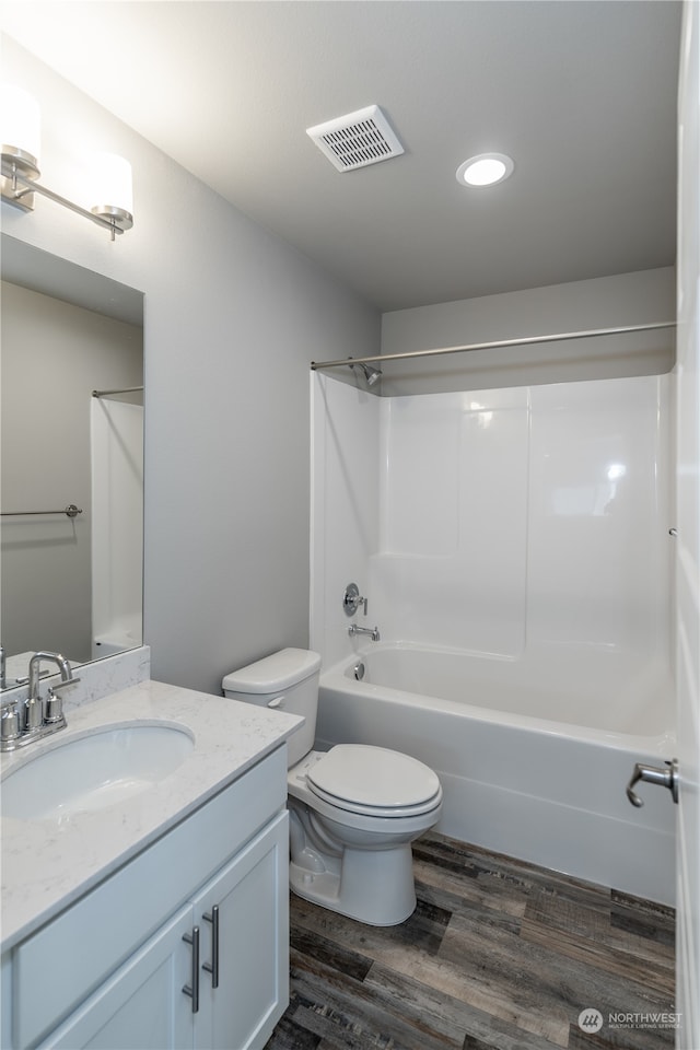 full bathroom featuring hardwood / wood-style floors, vanity, toilet, and bathing tub / shower combination