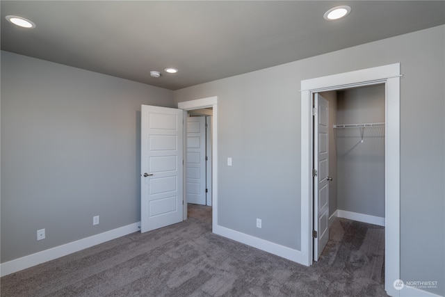 unfurnished bedroom with a closet and dark carpet