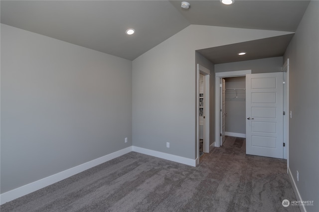 carpeted empty room featuring vaulted ceiling