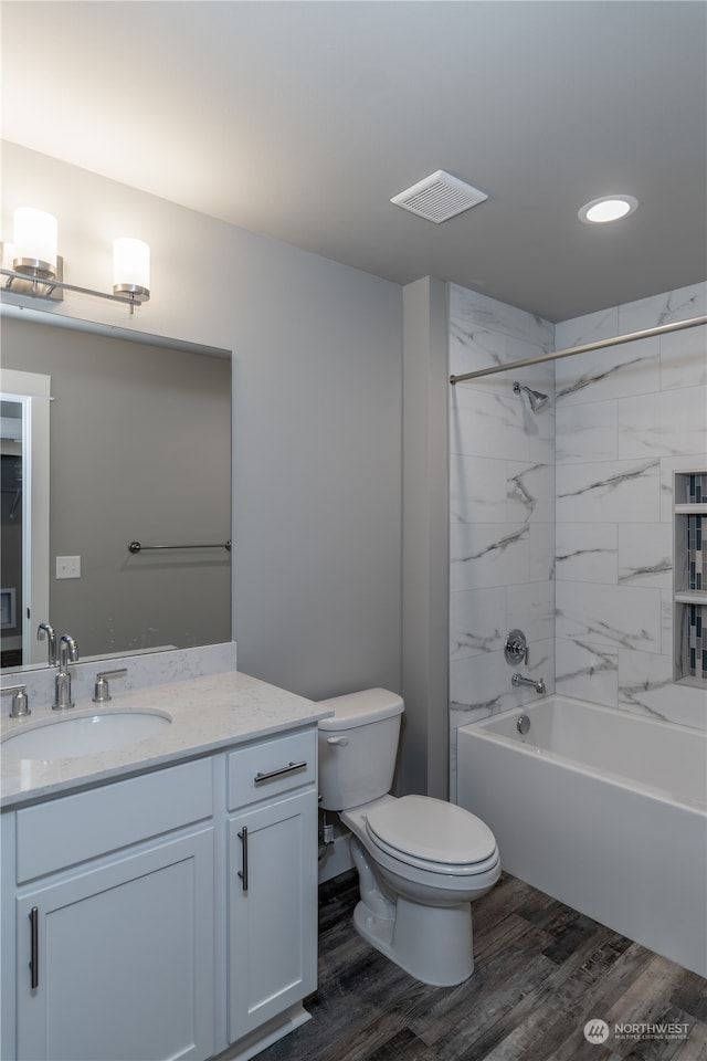 full bathroom featuring hardwood / wood-style flooring, vanity, toilet, and tiled shower / bath