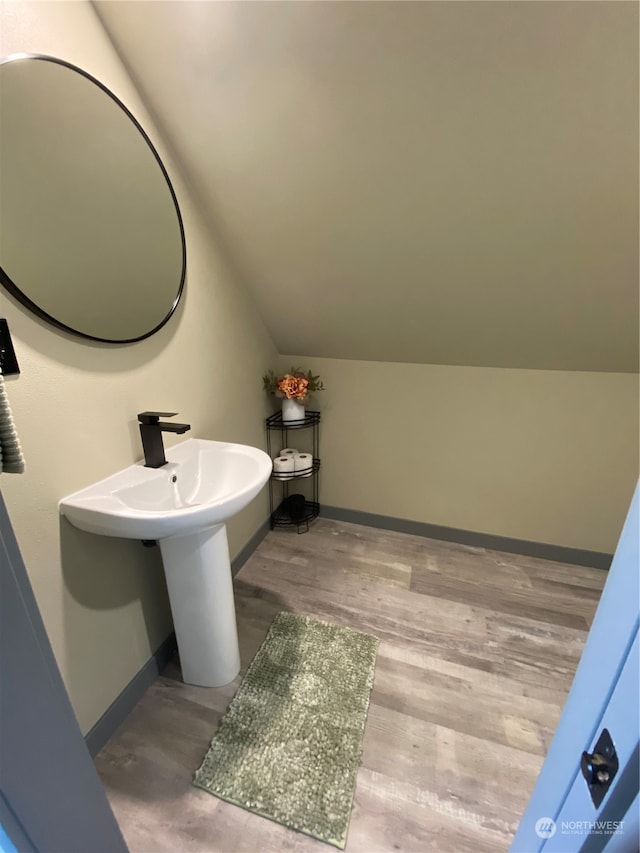 bathroom with vaulted ceiling and hardwood / wood-style flooring