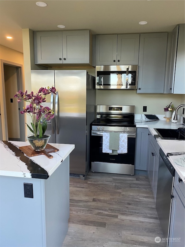 kitchen with gray cabinets, light wood-type flooring, sink, and appliances with stainless steel finishes