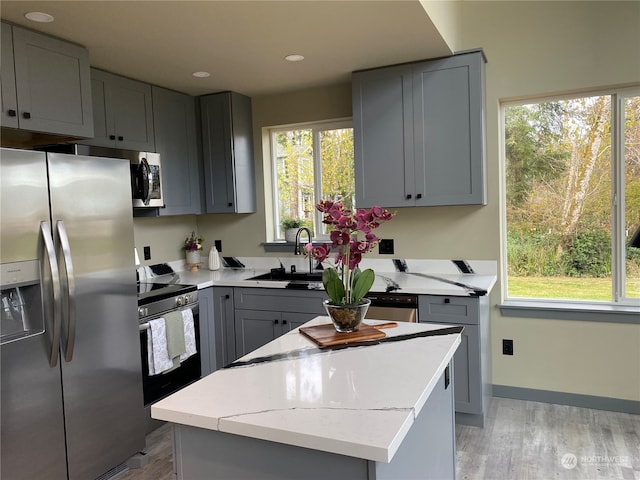 kitchen featuring gray cabinetry, a center island, a healthy amount of sunlight, and appliances with stainless steel finishes