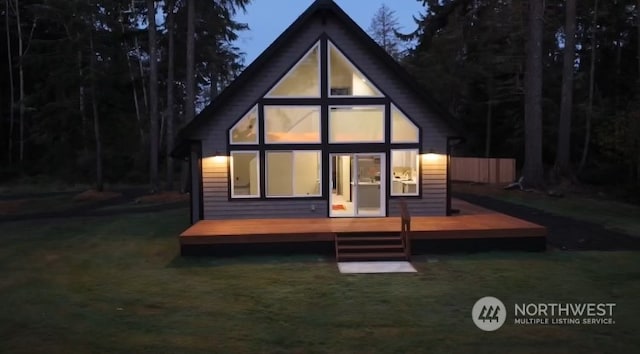 rear view of property featuring a lawn and a deck