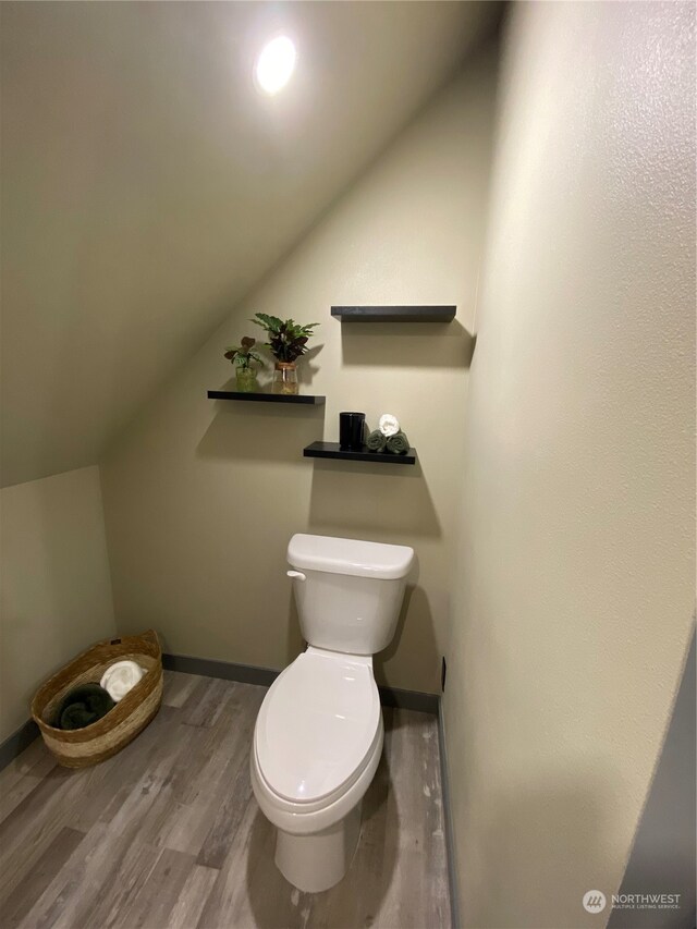 bathroom featuring hardwood / wood-style floors, lofted ceiling, and toilet