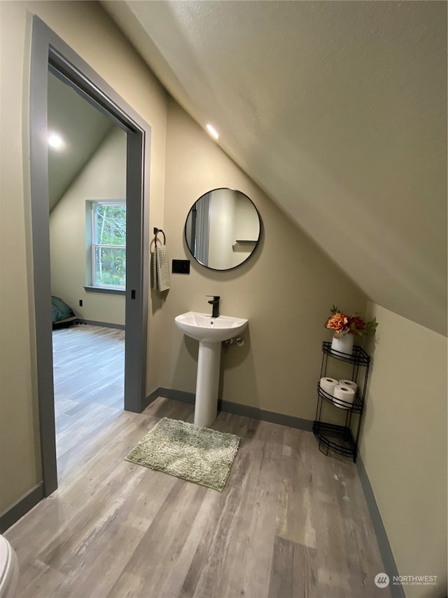 bathroom featuring a textured ceiling, vaulted ceiling, and hardwood / wood-style flooring