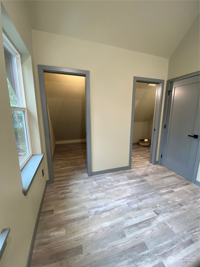 unfurnished bedroom featuring vaulted ceiling and light hardwood / wood-style flooring