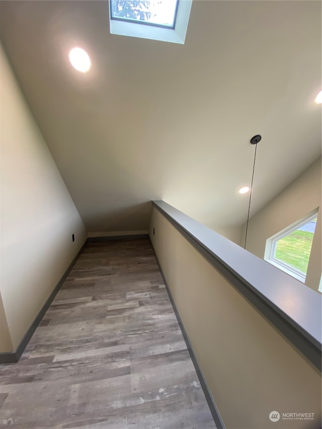 hallway with light wood-type flooring and a skylight