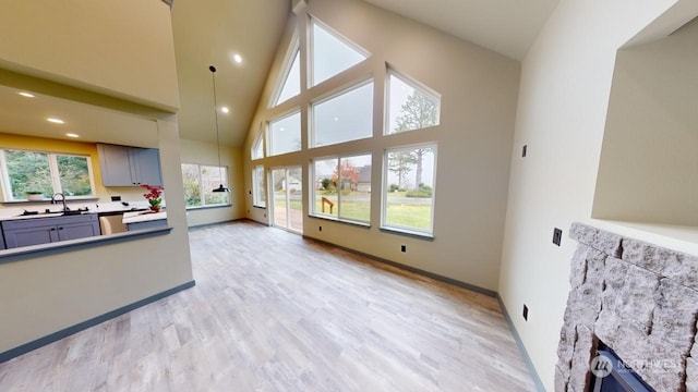 living room featuring light wood-type flooring, high vaulted ceiling, and sink