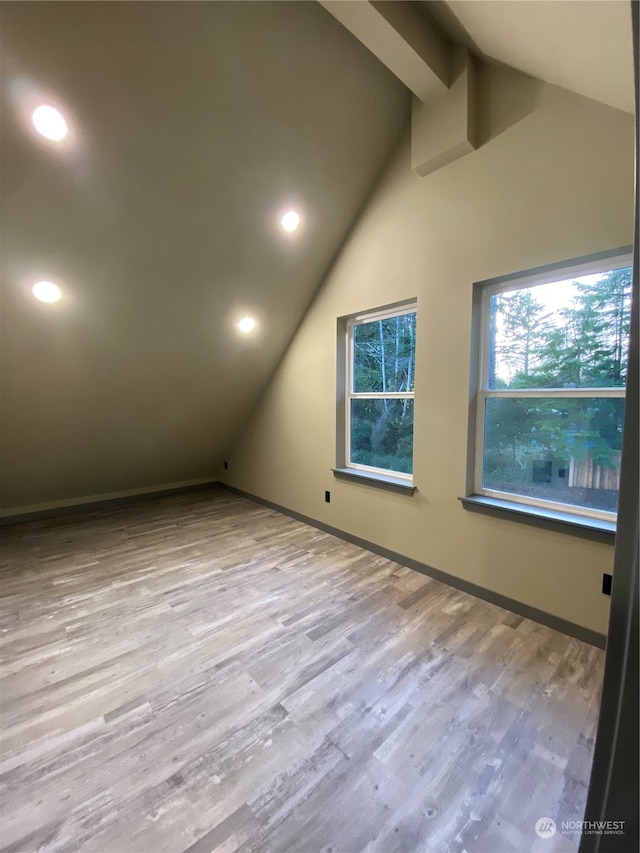 bonus room with vaulted ceiling with beams and light wood-type flooring