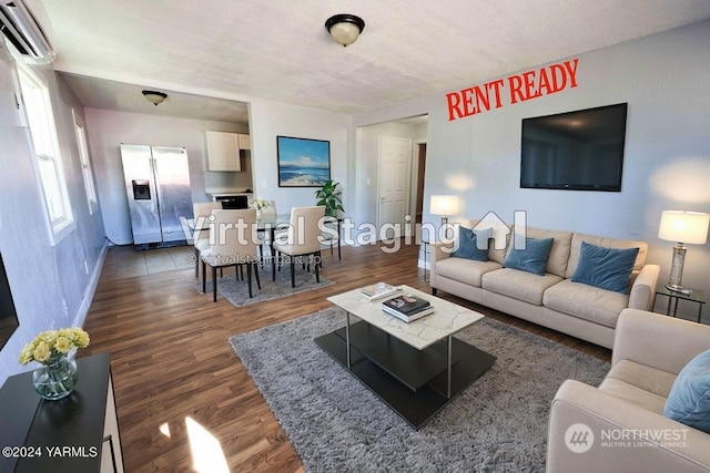 living room with a wall mounted air conditioner, dark hardwood / wood-style floors, and a textured ceiling