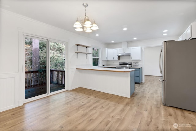 22222 Bluewater Dr SE, Yelm, WA 98597 - kitchen with stainless steel appliances, a peninsula, crown molding, a chandelier, and under cabinet range hood