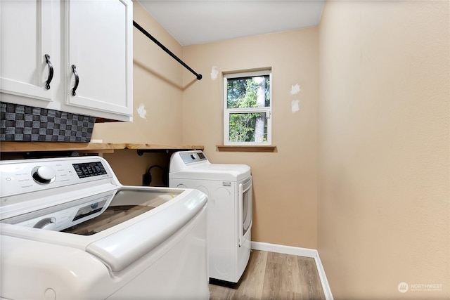 22222 Bluewater Dr SE, Yelm, WA 98597 - washroom with washing machine and clothes dryer, light wood-style floors, baseboards, and cabinet space