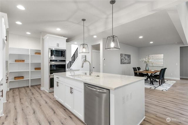 kitchen featuring sink, appliances with stainless steel finishes, decorative light fixtures, white cabinets, and light wood-type flooring