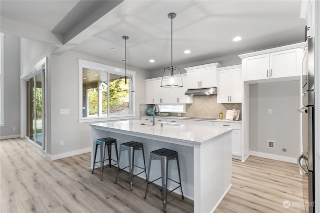 kitchen featuring white cabinets, an island with sink, light hardwood / wood-style floors, and sink