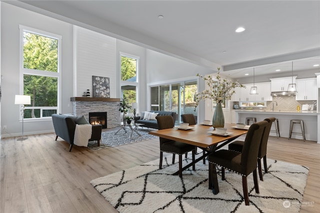 dining area featuring plenty of natural light, light hardwood / wood-style floors, and a stone fireplace