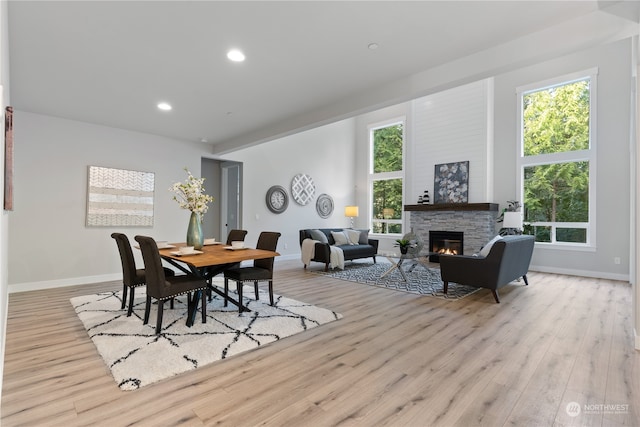 dining room featuring plenty of natural light, a stone fireplace, and light wood-type flooring