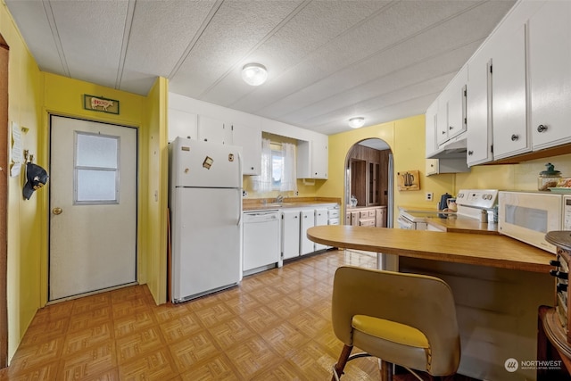 kitchen featuring white cabinets, white appliances, kitchen peninsula, light parquet flooring, and a textured ceiling