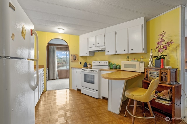 kitchen with white appliances, light parquet floors, white cabinetry, a kitchen breakfast bar, and a textured ceiling