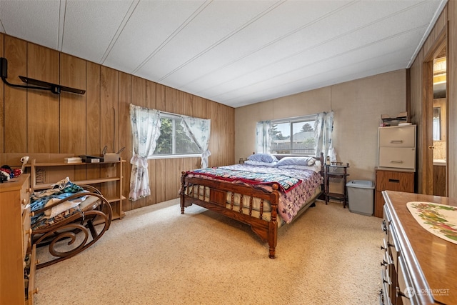 bedroom featuring multiple windows, light colored carpet, and wooden walls