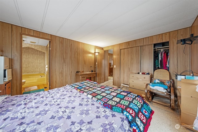 bedroom with a closet, connected bathroom, and wood walls