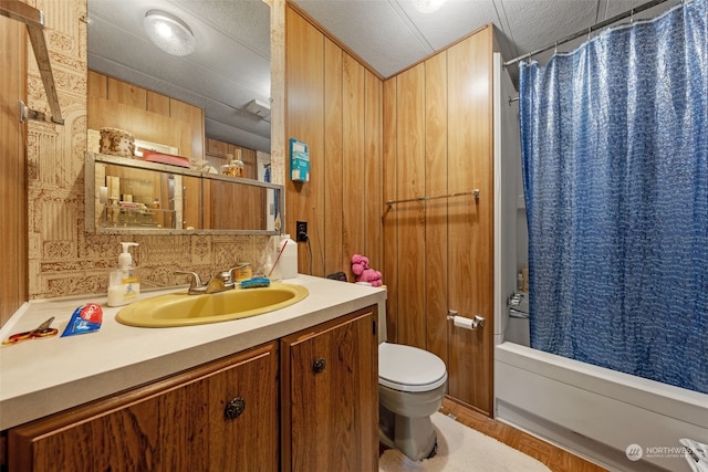 full bathroom with shower / tub combo with curtain, toilet, a textured ceiling, vanity, and wooden walls