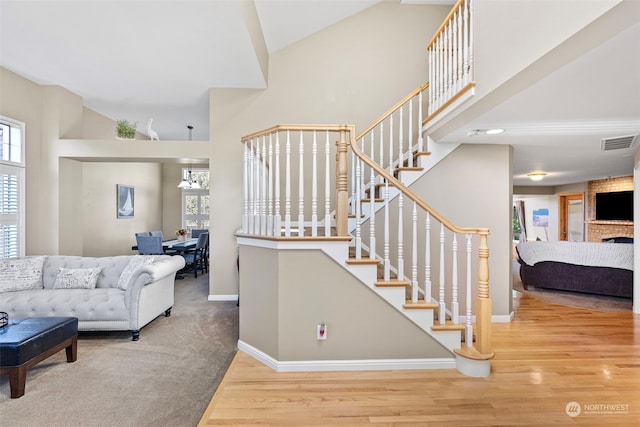 living room featuring a brick fireplace, wood-type flooring, and high vaulted ceiling