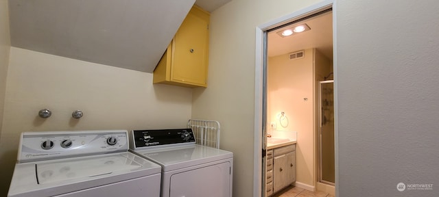 laundry room with cabinets, light tile patterned floors, and washer and dryer