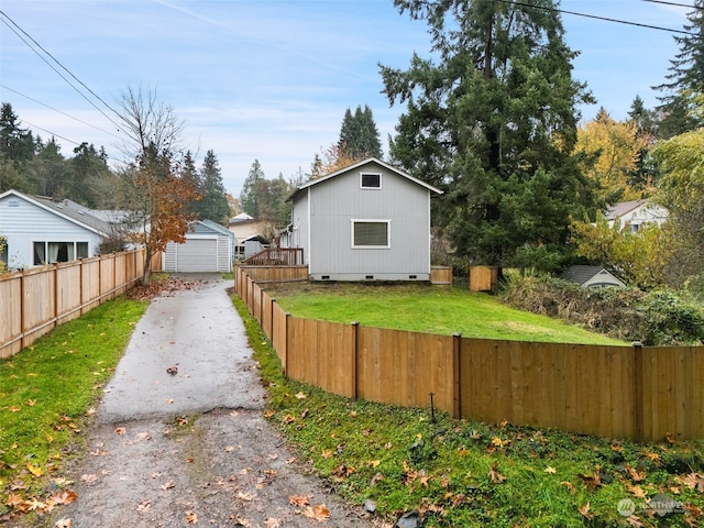 view of property exterior featuring a garage, a lawn, and an outbuilding