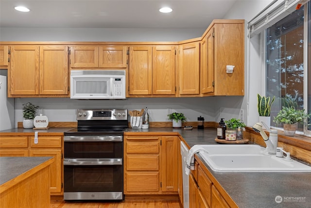 kitchen featuring sink, light hardwood / wood-style floors, and white appliances