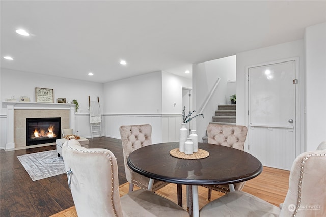 dining space featuring a tile fireplace and wood-type flooring