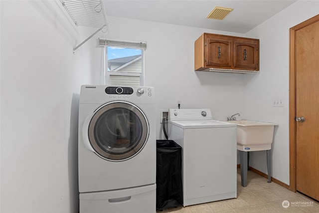 clothes washing area featuring cabinets and washing machine and dryer