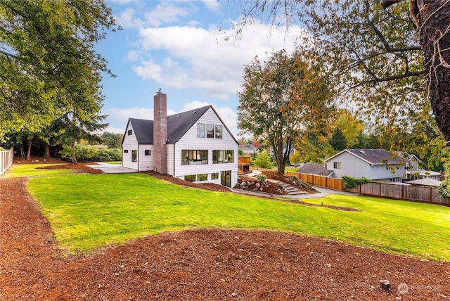 rear view of property featuring a lawn and a patio area