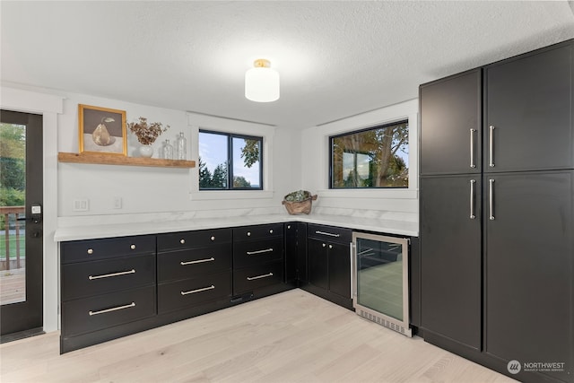 kitchen featuring a textured ceiling, wine cooler, and light hardwood / wood-style flooring