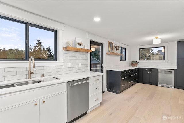 kitchen with white cabinets, light hardwood / wood-style floors, sink, and dishwasher