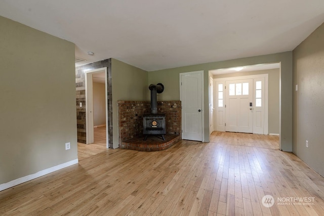 foyer entrance featuring light wood-type flooring and a wood stove