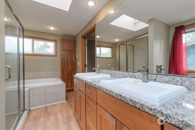 bathroom with plenty of natural light, wood-type flooring, a skylight, and vanity