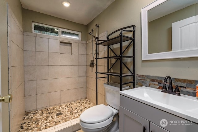 bathroom featuring tiled shower, vanity, and toilet