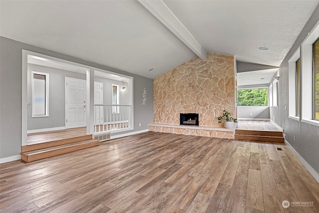 unfurnished living room with a fireplace, lofted ceiling with beams, and wood-type flooring