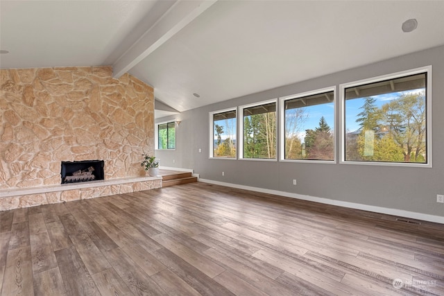 unfurnished living room with a fireplace, lofted ceiling with beams, and wood-type flooring