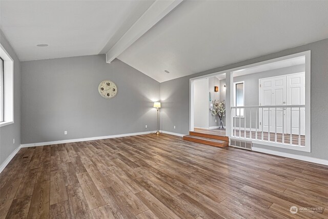 empty room featuring wood-type flooring and vaulted ceiling with beams