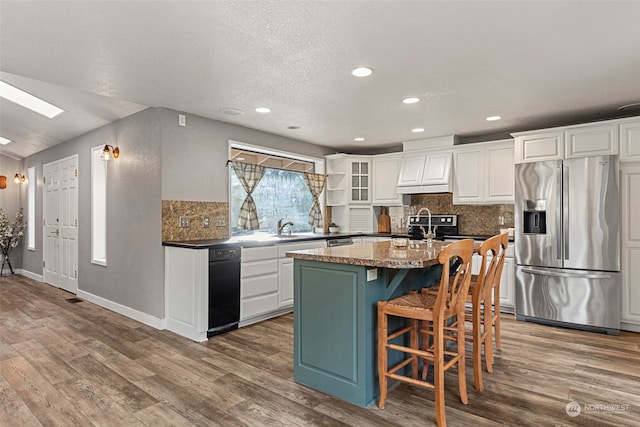 kitchen featuring a kitchen bar, a kitchen island with sink, hardwood / wood-style floors, stainless steel fridge with ice dispenser, and white cabinetry