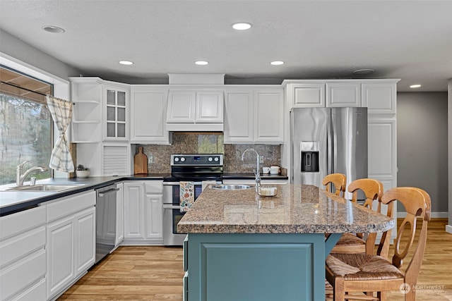 kitchen featuring light hardwood / wood-style floors, sink, a kitchen island with sink, and appliances with stainless steel finishes