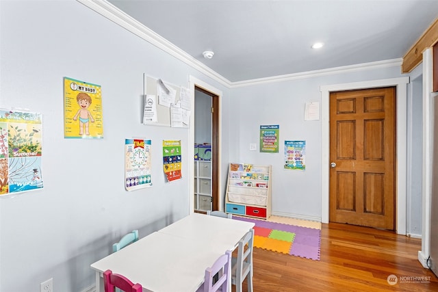 recreation room with wood-type flooring and crown molding