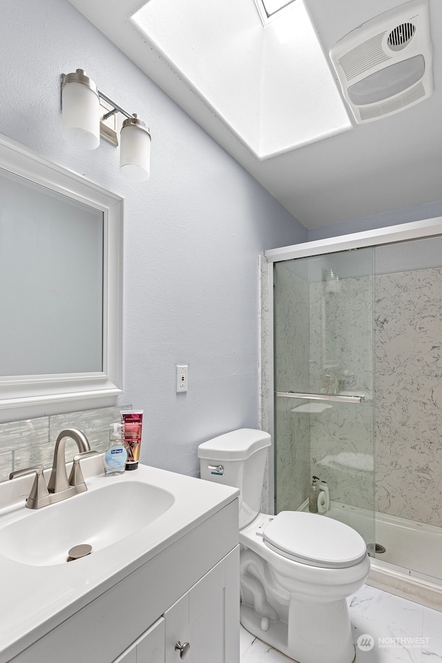 bathroom featuring vanity, a skylight, toilet, and a shower with shower door