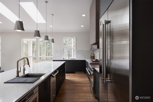 kitchen with stainless steel appliances, dark hardwood / wood-style flooring, hanging light fixtures, sink, and tasteful backsplash