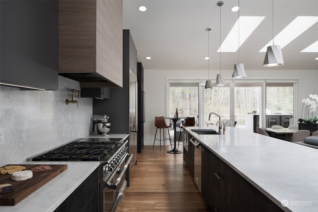 kitchen featuring appliances with stainless steel finishes, decorative light fixtures, dark hardwood / wood-style floors, sink, and a skylight