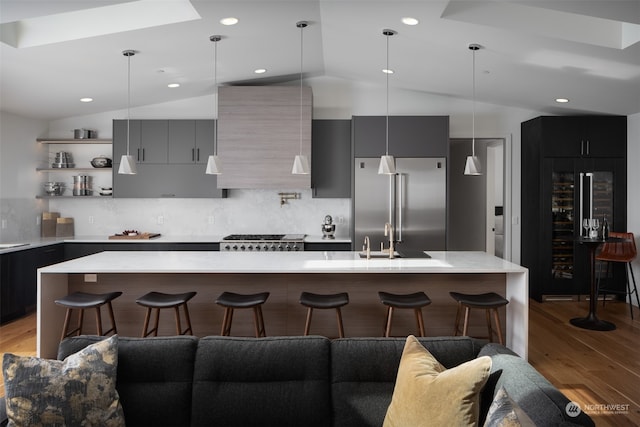 kitchen featuring lofted ceiling, a breakfast bar, a kitchen island with sink, and appliances with stainless steel finishes